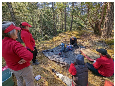 Aa wilderness First Aid instructor teaching spinal immobilization in a Wilderness First Aid course in an outdoor setting